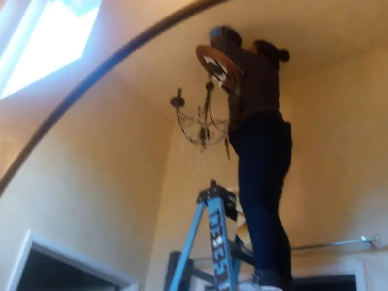 Electrician installing a chandelier in a Clearfield residence